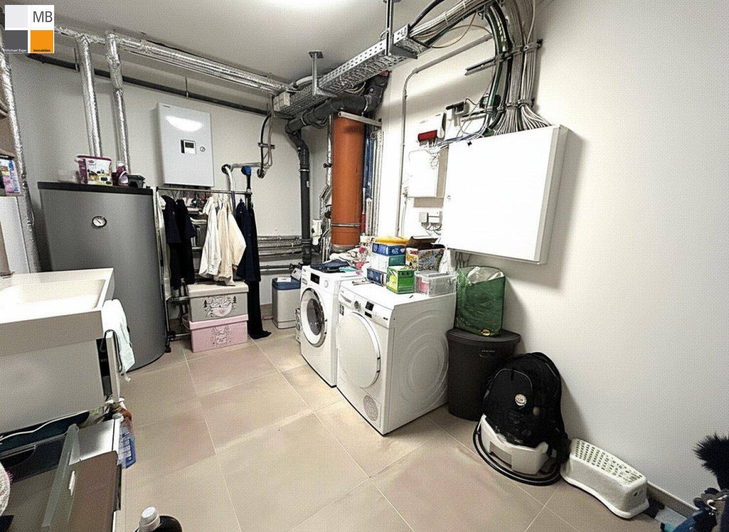 Funktionaler Hauswirtschaftsraum im Keller mit Waschmaschine, Trockner und Heizungsanlage.
