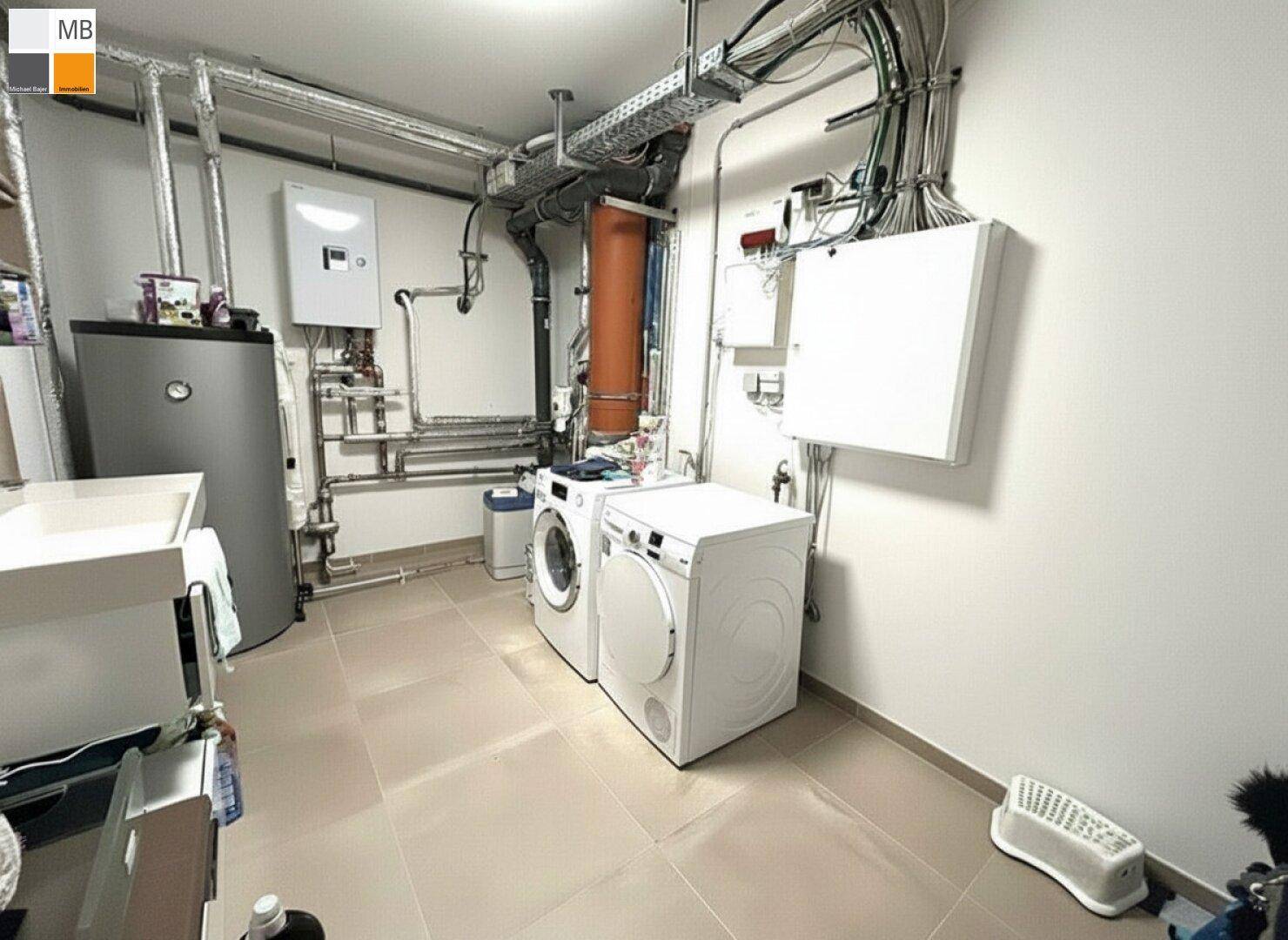 Funktionaler Hauswirtschaftsraum im Keller mit Waschmaschine, Trockner und Heizungsanlage.