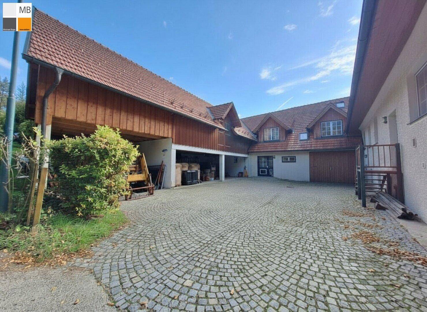 Großer gepflasterter Hofbereich mit mehreren Gebäuden und Garagenzugang.