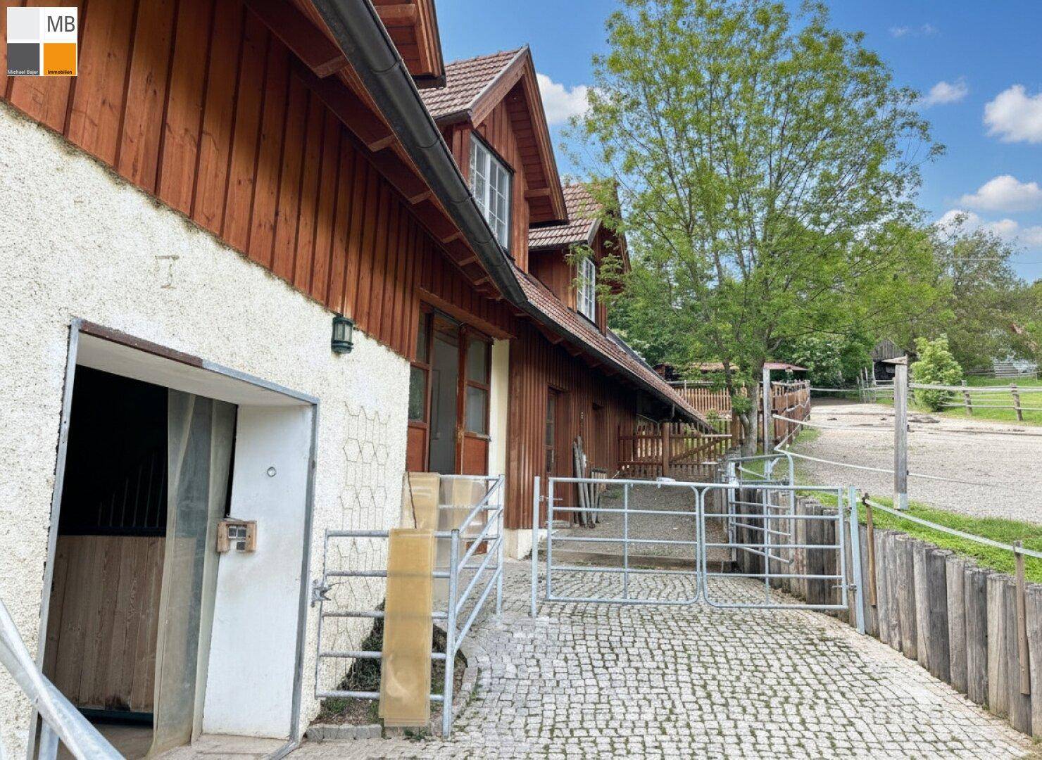 Eingangsbereich eines ländlichen Gebäudes mit gepflastertem Hof und Metalltoren.