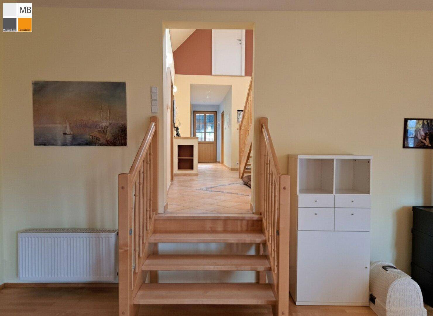 Eingangsbereich mit Holztreppe, Heizkörper und Blick in den hinteren Flur.