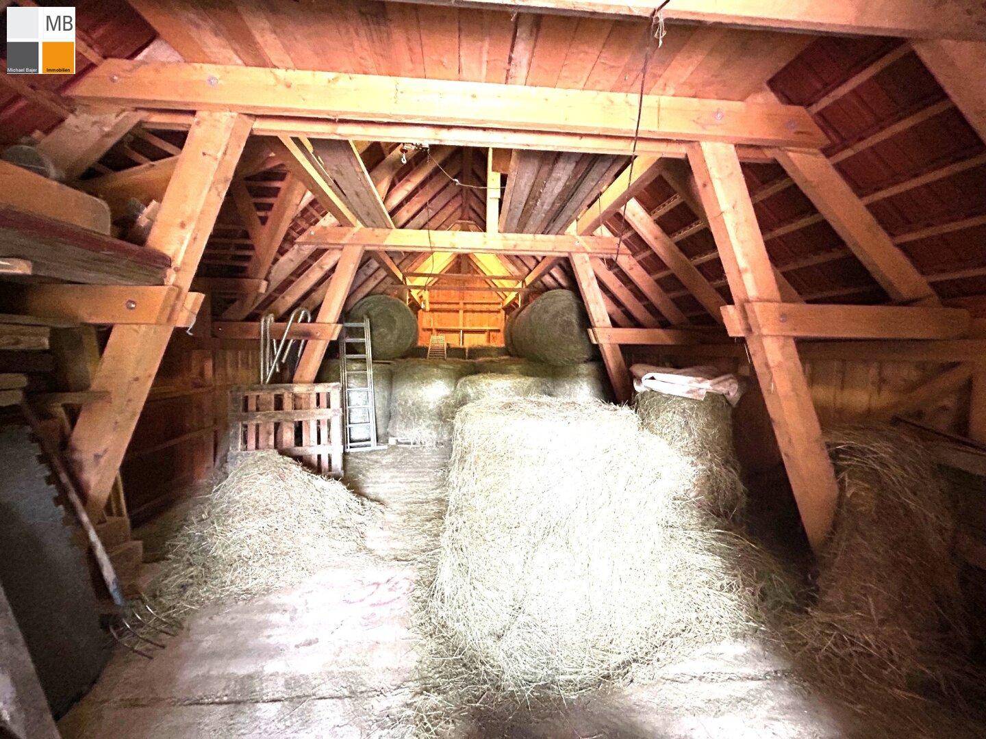 Geräumiger Dachboden mit Holzbalken und Heuballen, ideal als Lagerfläche.