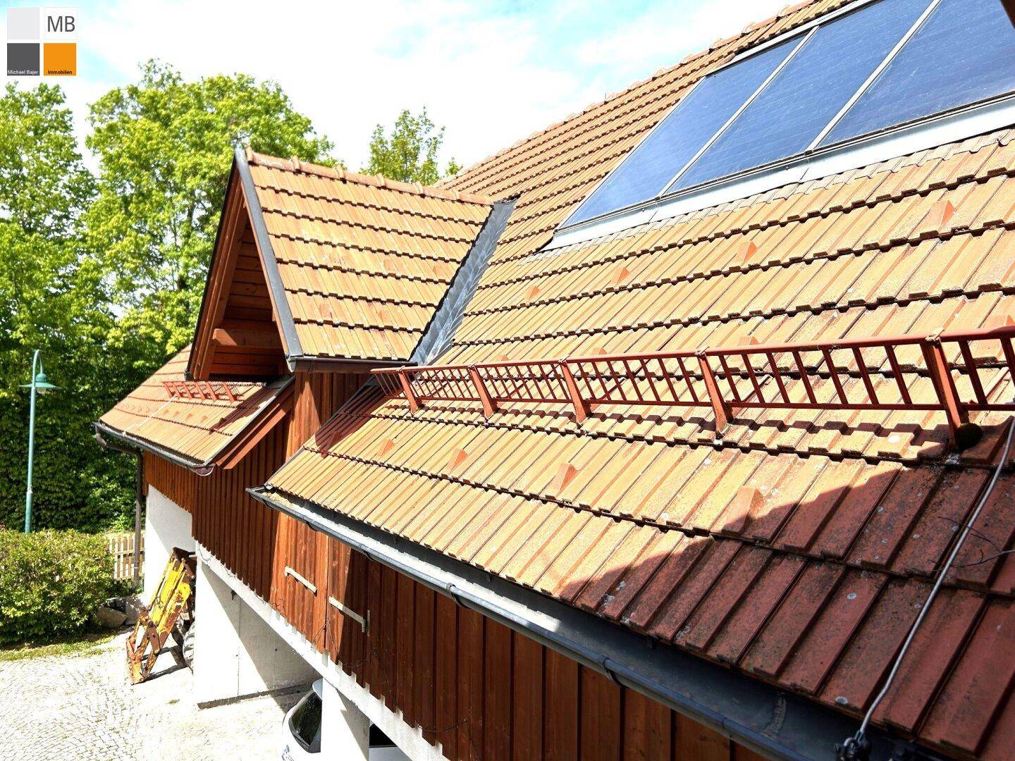 Detailansicht des Daches mit Ziegeln und Photovoltaikanlage unter blauem Himmel.