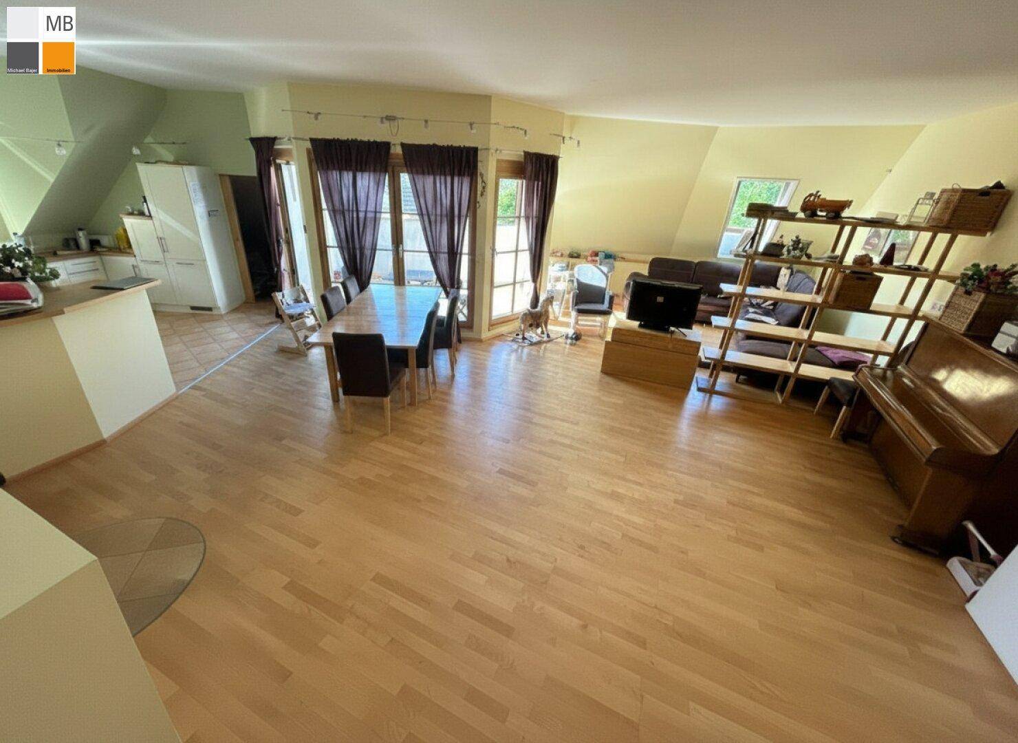 Geräumiger offener Wohn-Essbereich mit Holzboden, Esstisch und Blick ins Grüne.