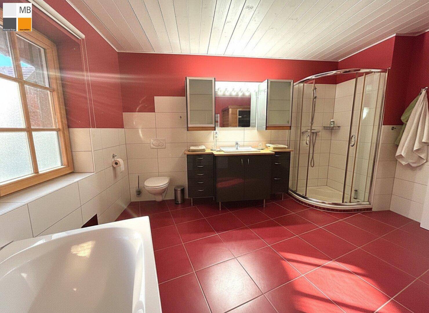 Helles Badezimmer mit roten Bodenfliesen, Badewanne, Dusche und Waschtisch.