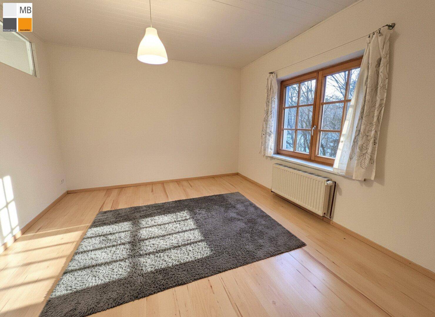 Helles Schlafzimmer mit Holzboden, großem Fenster und viel Tageslicht.