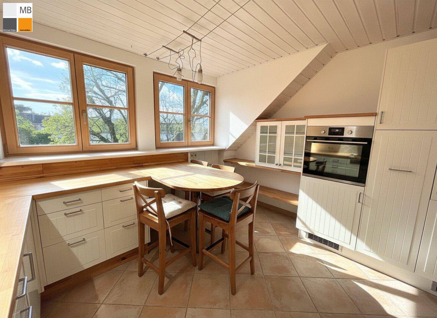 Helle Einbauküche im Dachgeschoss mit Holzdetails, integriertem Backofen und Essbereich.