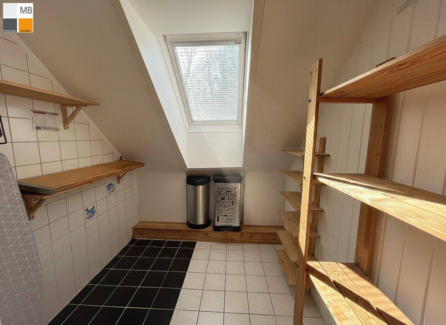 Praktischer Abstellraum im Dachgeschoss mit Holzregalen und Dachfenster für Tageslicht.