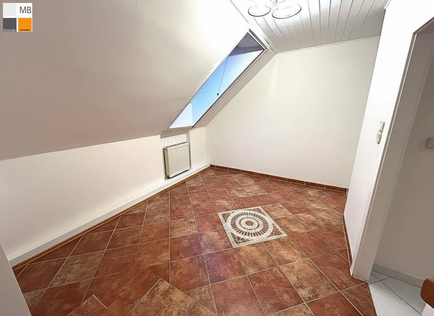 Raum im Dachgeschoss mit Terrakotta-Fliesenboden und einem Dachfenster.