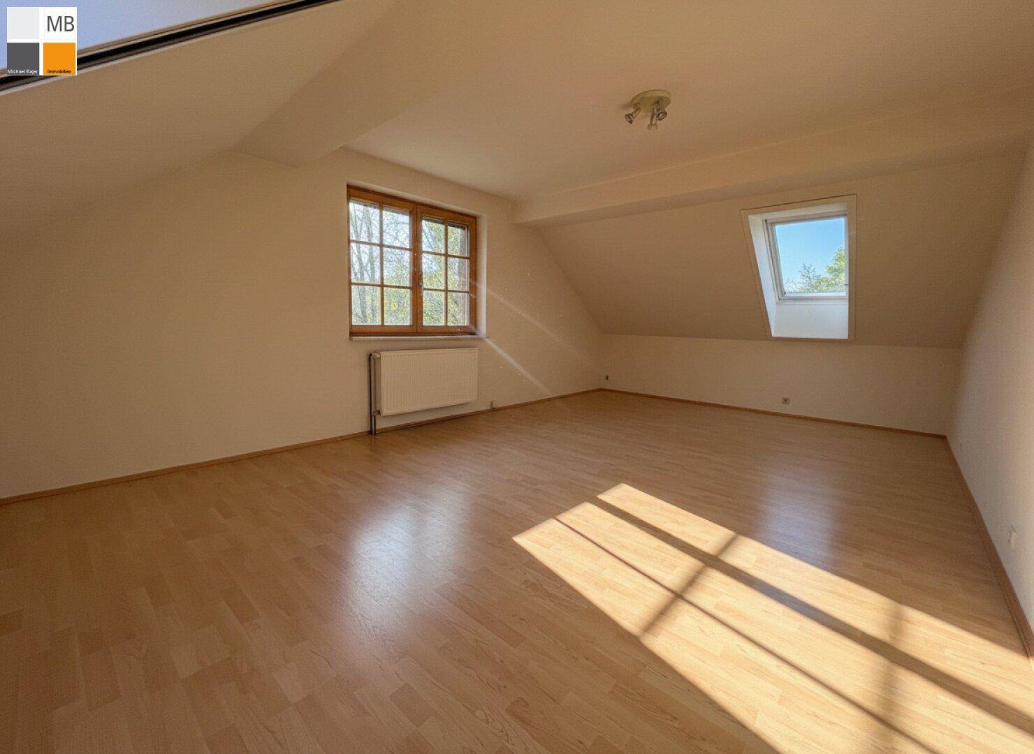 Helles Schlafzimmer im Dachgeschoss mit Holzboden, Fenster und Dachfenster.