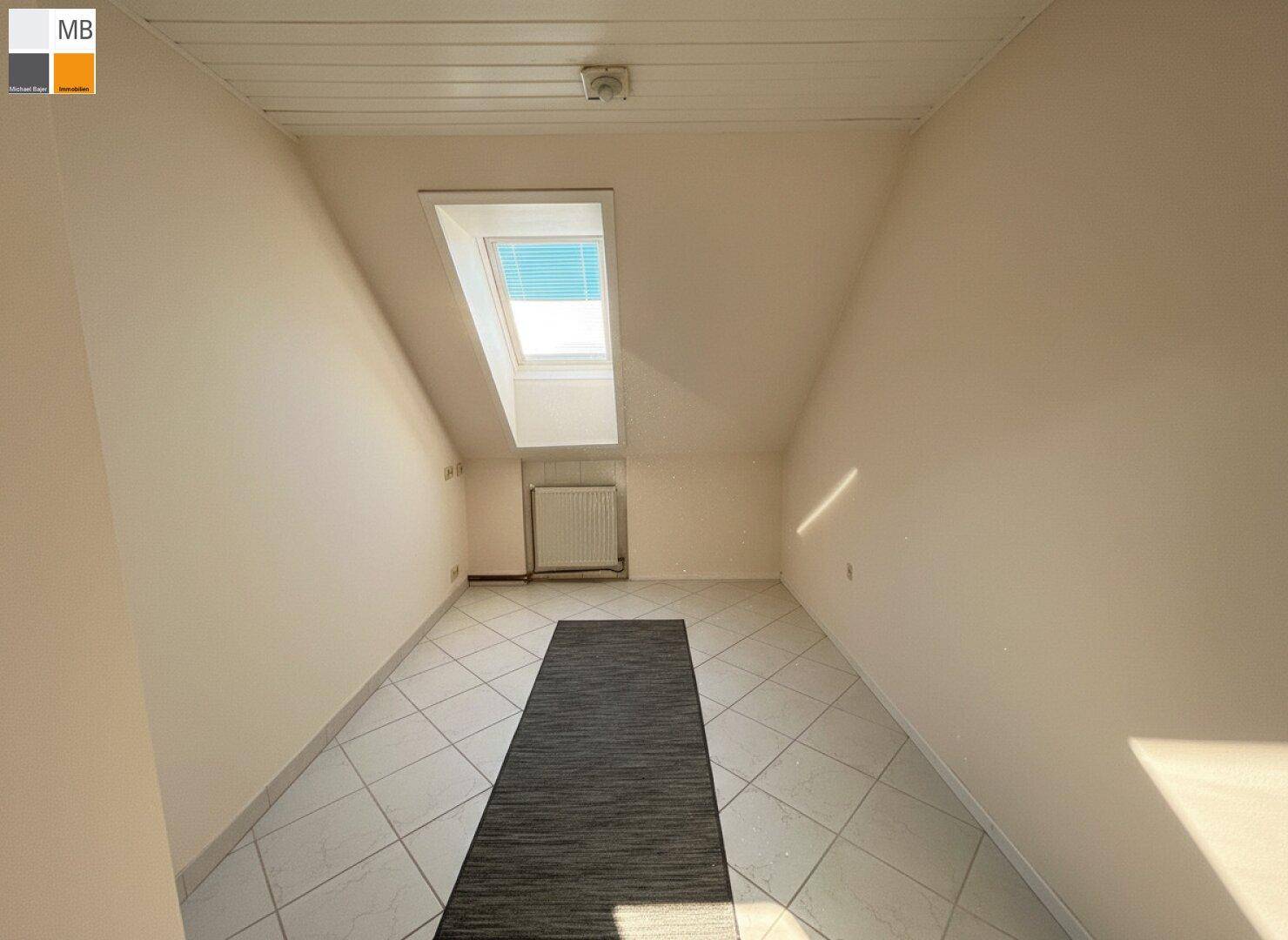 Kleiner Raum im Dachgeschoss mit weißen Fliesen, Heizkörper und Dachfenster.