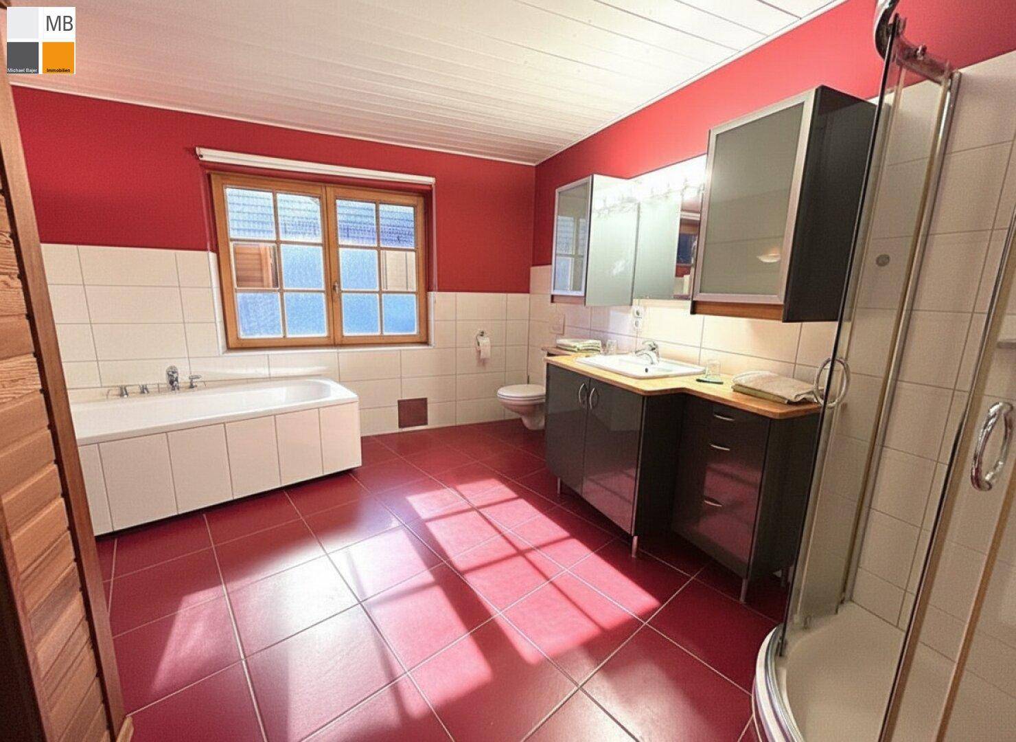 Geräumiges Badezimmer mit roten Fliesen, Badewanne, Dusche und Holzfenster.
