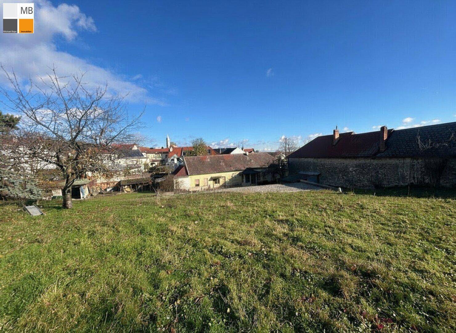 Weitläufige Grünfläche mit Blick auf traditionelle Gebäude und die umliegende Landschaft.