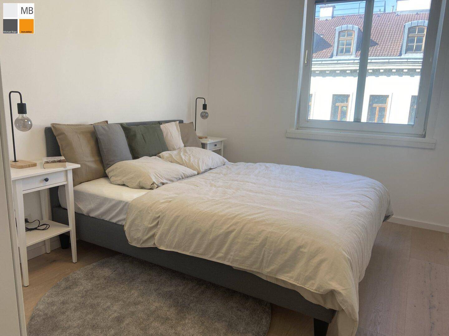 Gemütliches Schlafzimmer mit Doppelbett, Nachttischen und Blick auf die Stadt.