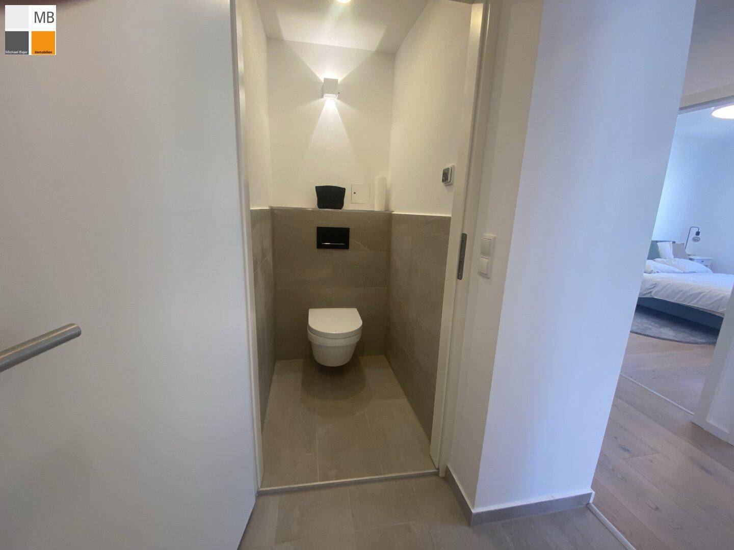 Modernes Gäste-WC mit Wand-WC und grauen Fliesen an Wänden und Boden.