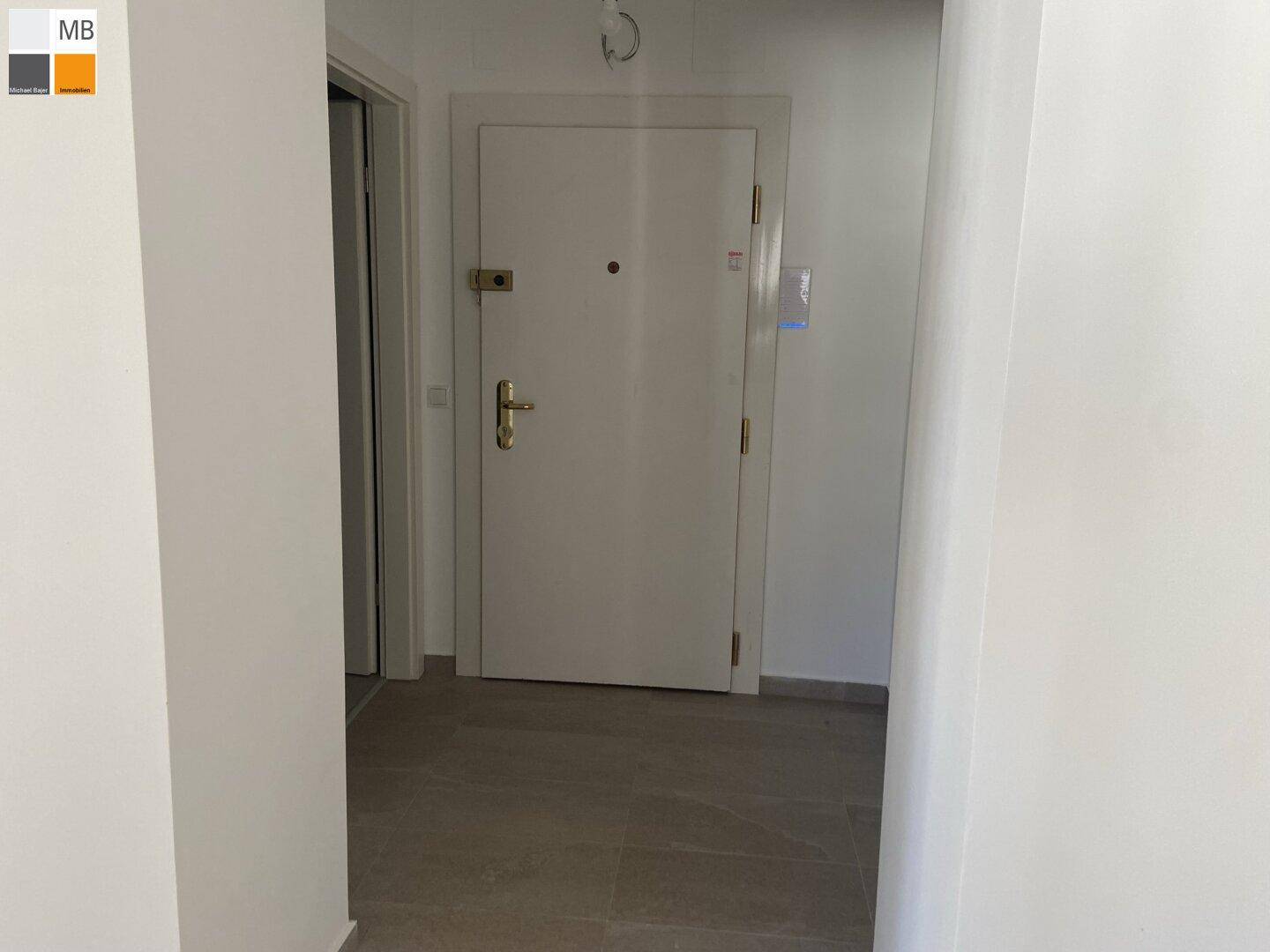 Heller Eingangsbereich mit moderner Wohnungstür und Fliesenboden.