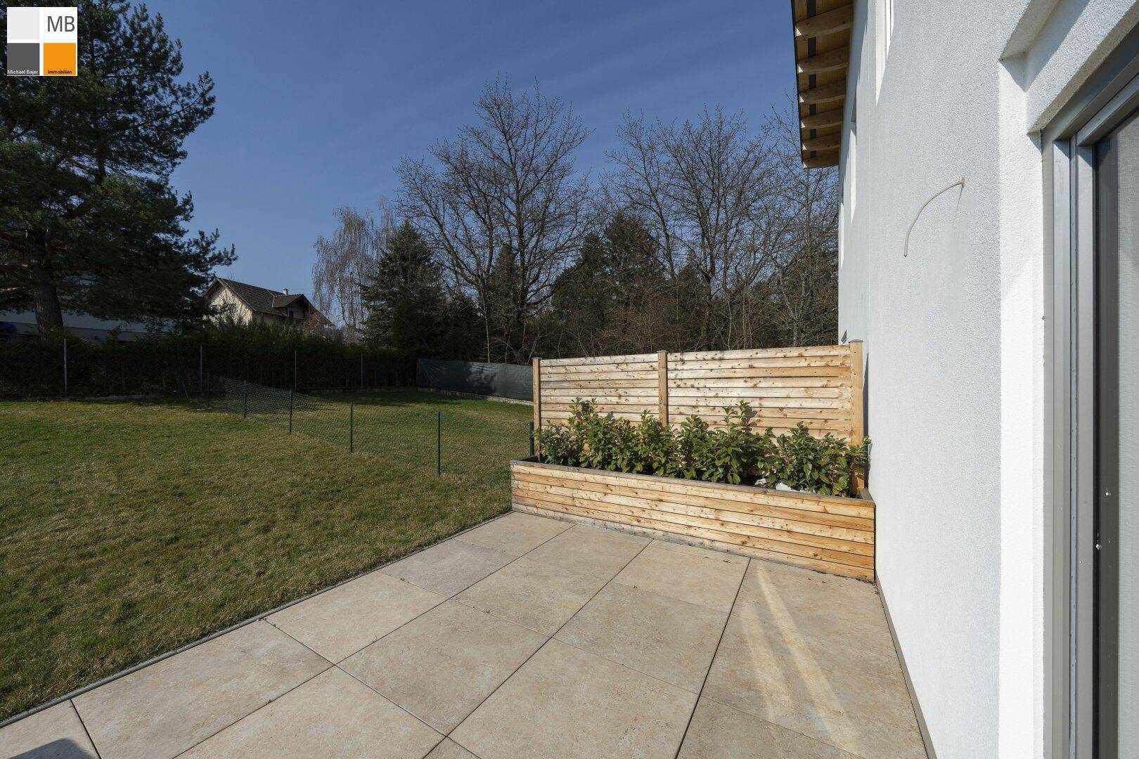 Geräumige Terrasse mit Holzelementen und Blick auf den weitläufigen Gartenbereich.