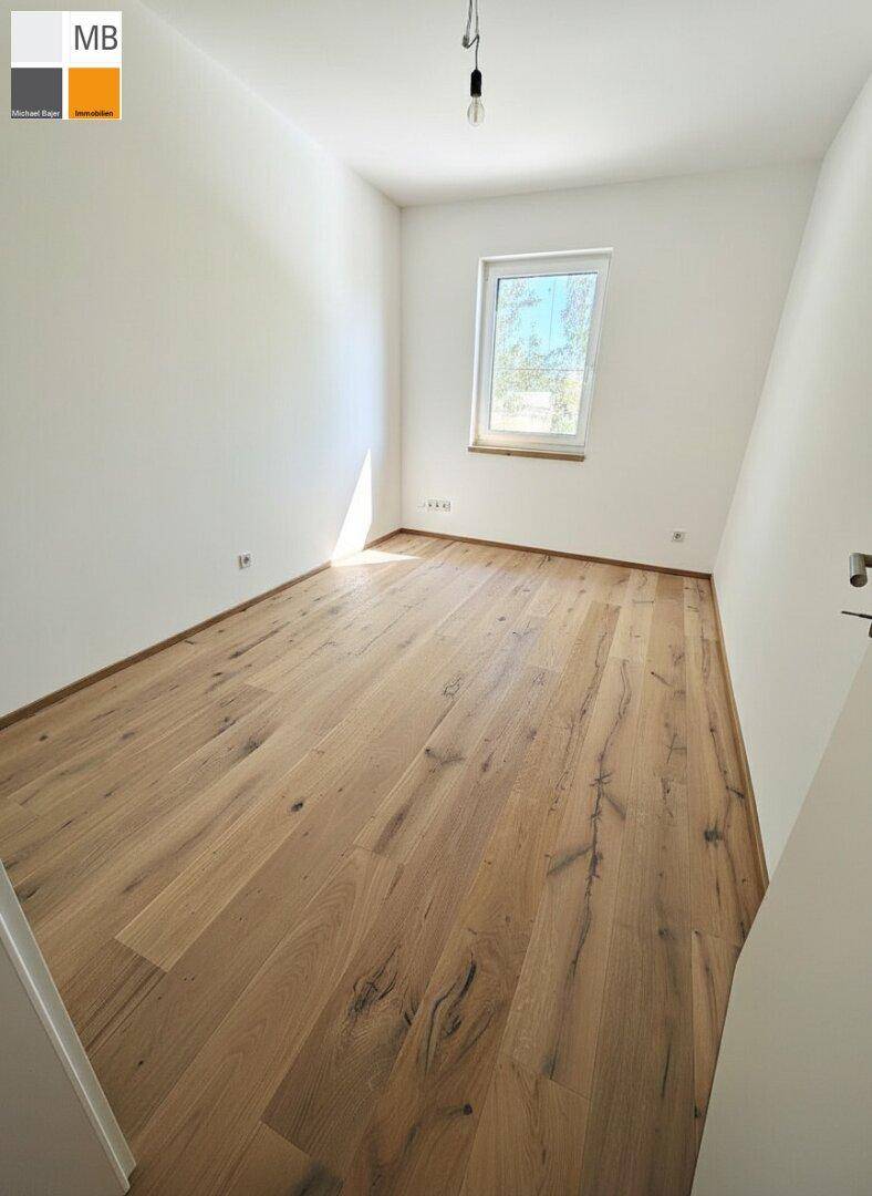 Lichtdurchflutetes Zimmer mit Holzdielenboden und einem Fenster, das viel Helligkeit bietet.