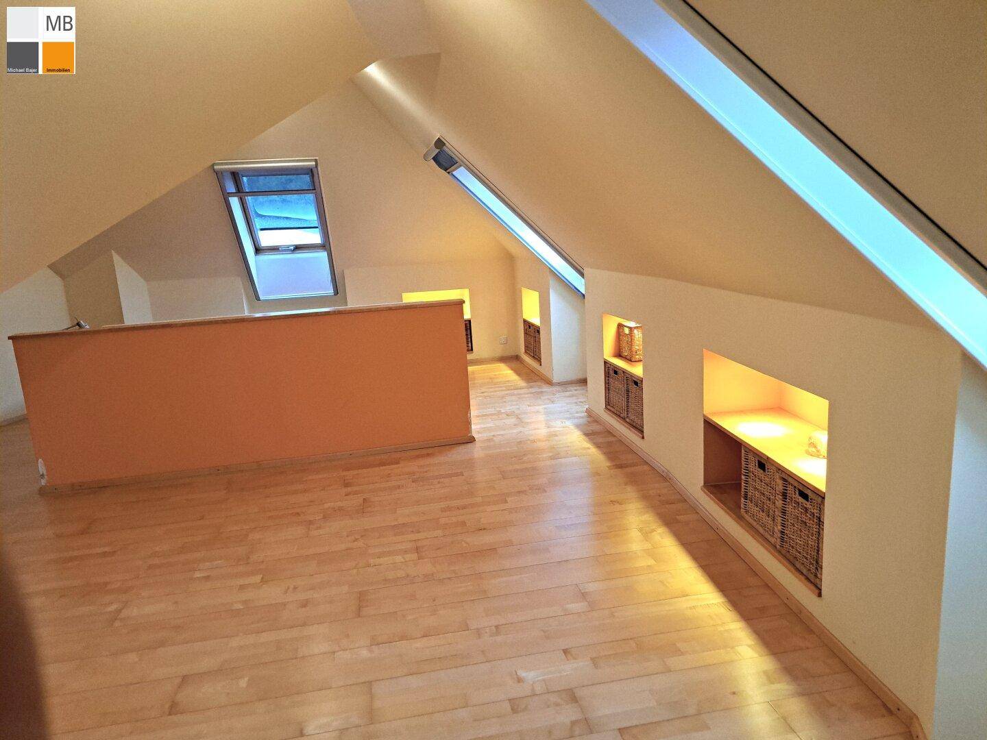Offener Dachbodenbereich mit Holzboden, Dachschrägen und Dachfenstern für natürliches Licht.