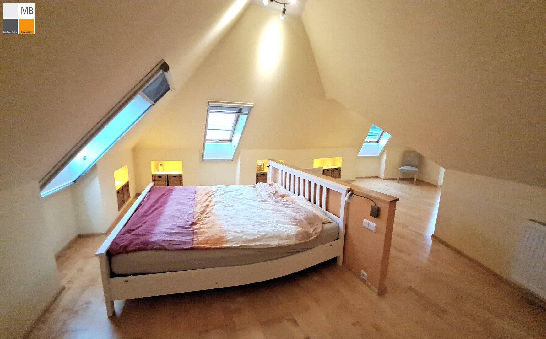 Gemütliches Schlafzimmer im Dachgeschoss mit Holzboden, Dachschrägen und Dachfenstern.