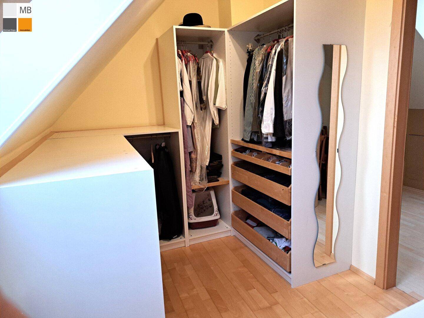 Praktischer begehbarer Kleiderschrank mit integrierten Regalen und Schubladen unter der Dachschräge.