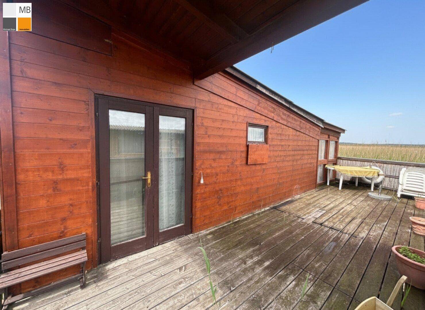 Geräumige Holzterrasse am Haus mit Sitzgelegenheiten und Blick auf die Umgebung.
