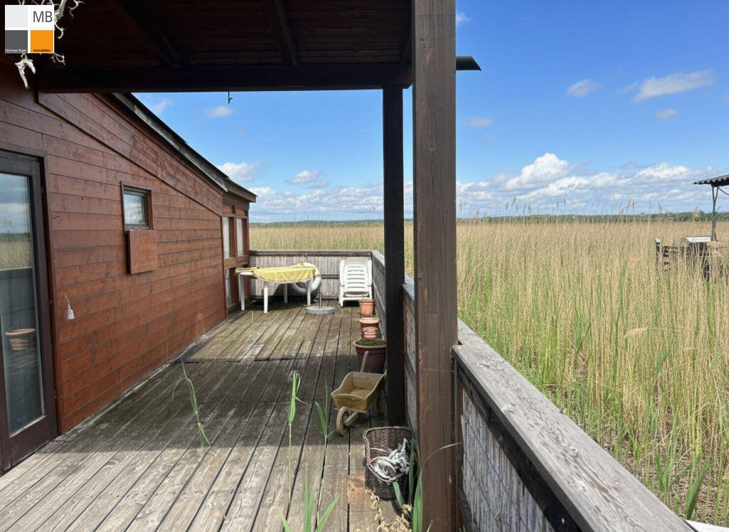Überdachte Holzterrasse mit Gartenmöbeln und weitem Blick auf die umliegende Natur.