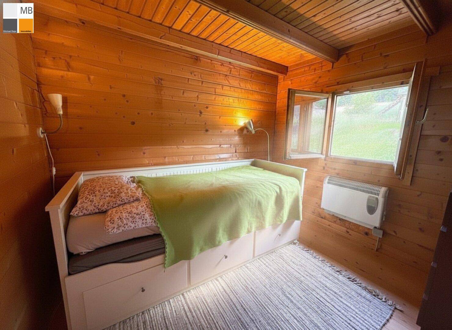 Gemütliches Schlafzimmer mit Holzverkleidung, Holzboden und einem praktischen Bett mit Stauraum.