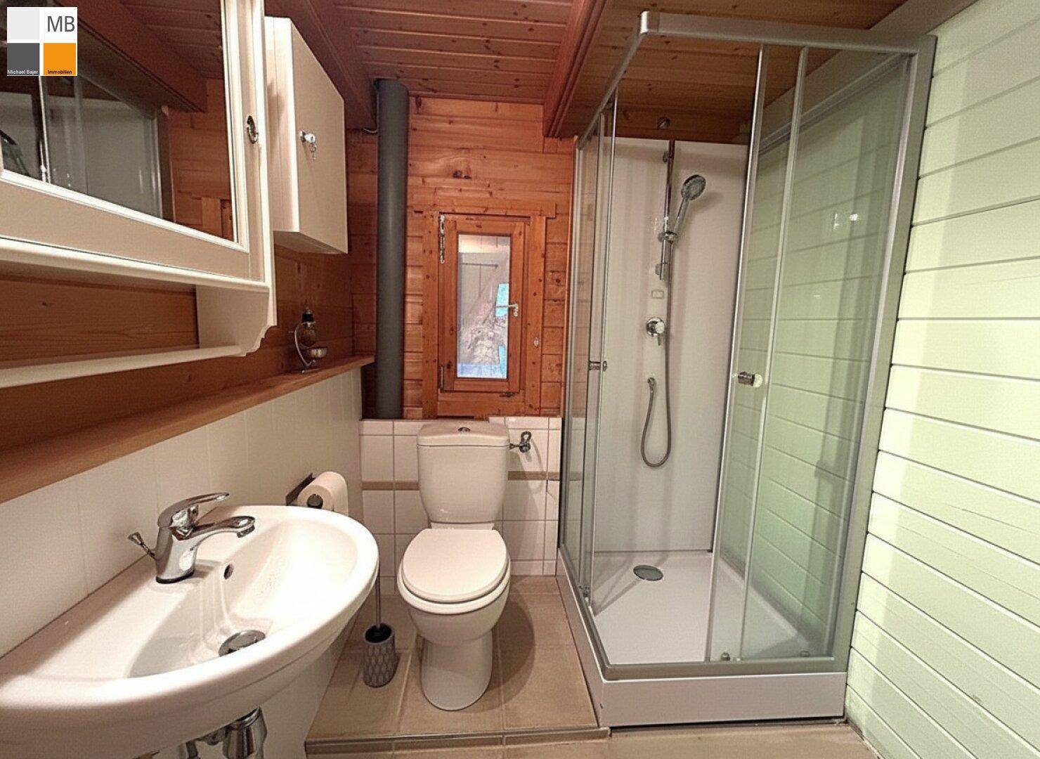Helles Badezimmer mit Duschkabine, WC, Waschbecken und einer Kombination aus Fliesen und Holzverkleidung.