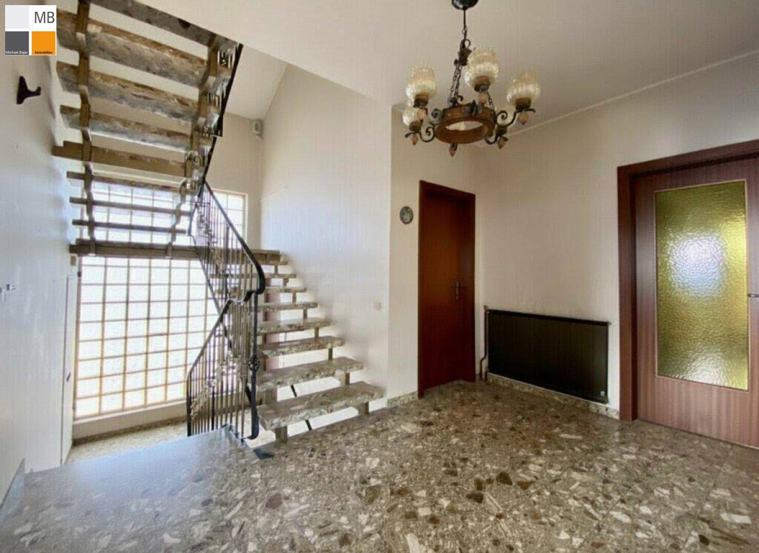 Heller Flur mit breiter Treppe, Marmorboden und dekorativer Glasbausteinwand für viel Tageslicht.