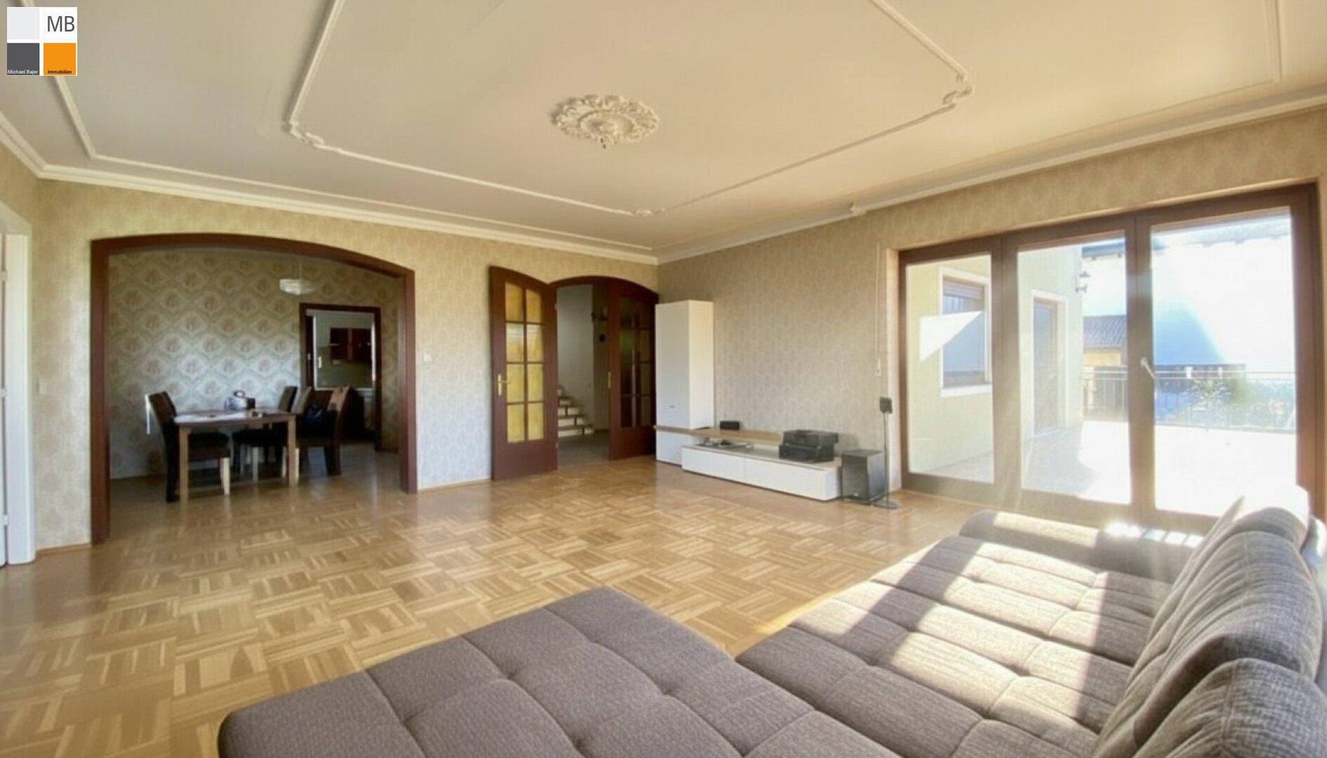 Geräumiges Wohnzimmer mit Parkettboden, Stuckdecke und offenem Übergang zum Essbereich.