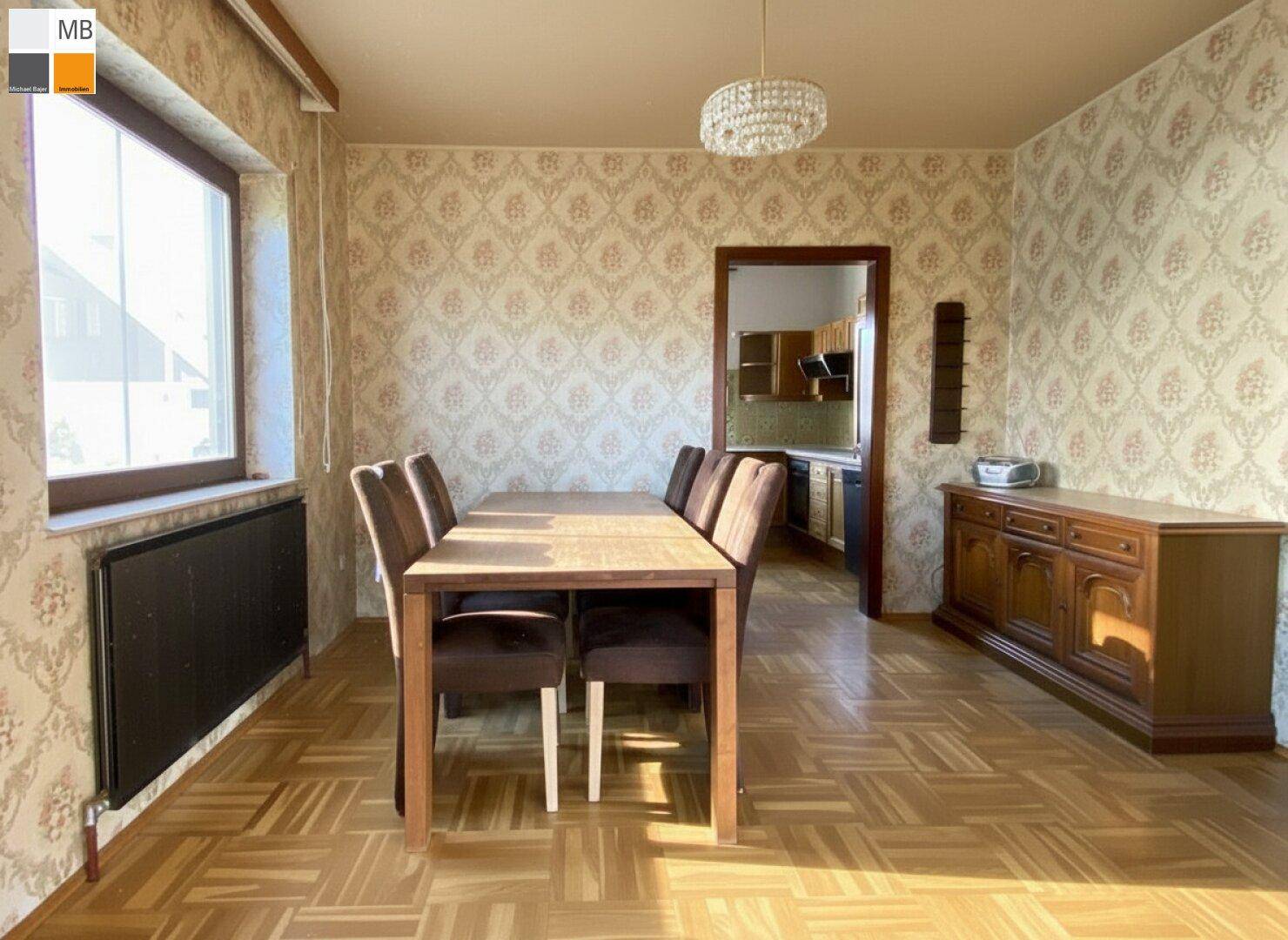 Gemütlicher Essbereich mit Parkettboden, gemusterter Tapete und großem Fenster für viel Tageslicht.