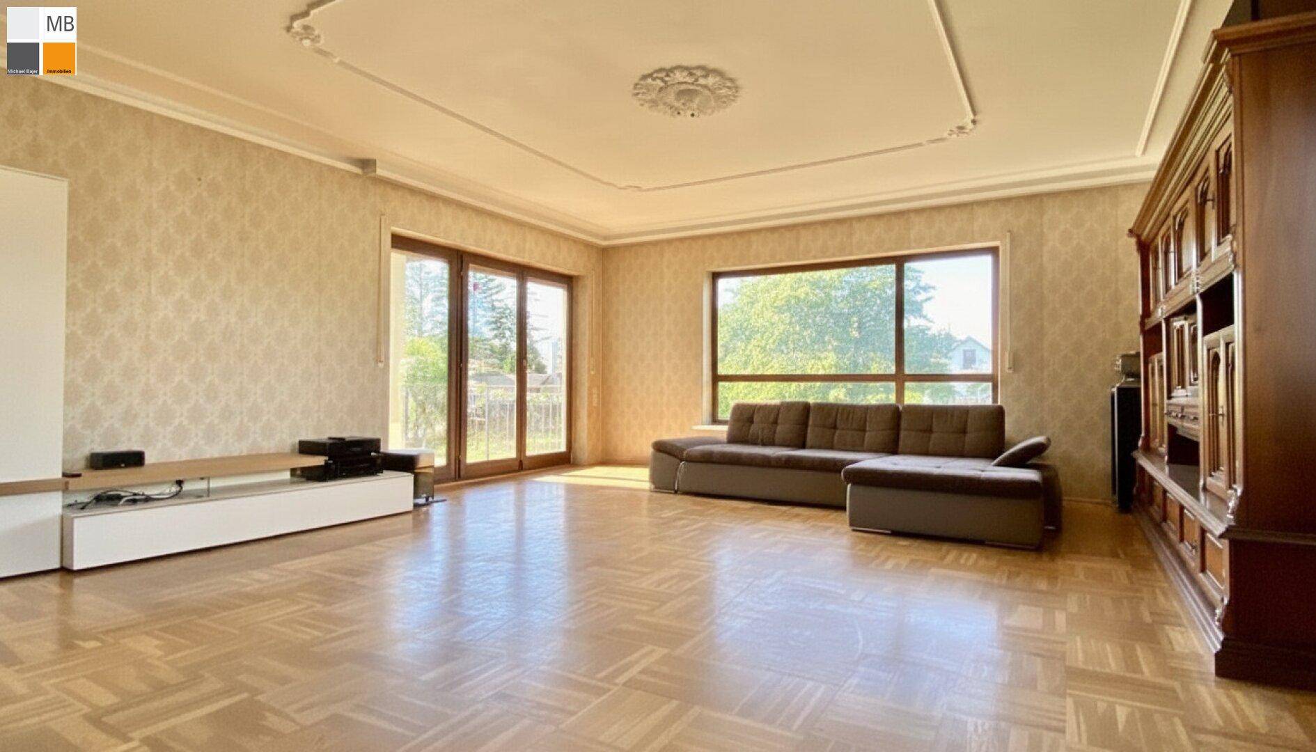Großes Wohnzimmer mit Parkettboden, Stuckdecke und direktem Zugang zur Terrasse.
