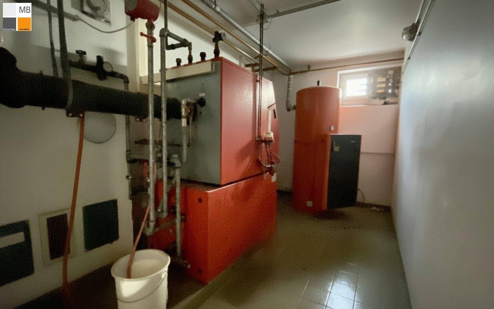 Heizungsraum mit großem Boiler und technischen Installationen im Kellerbereich.
