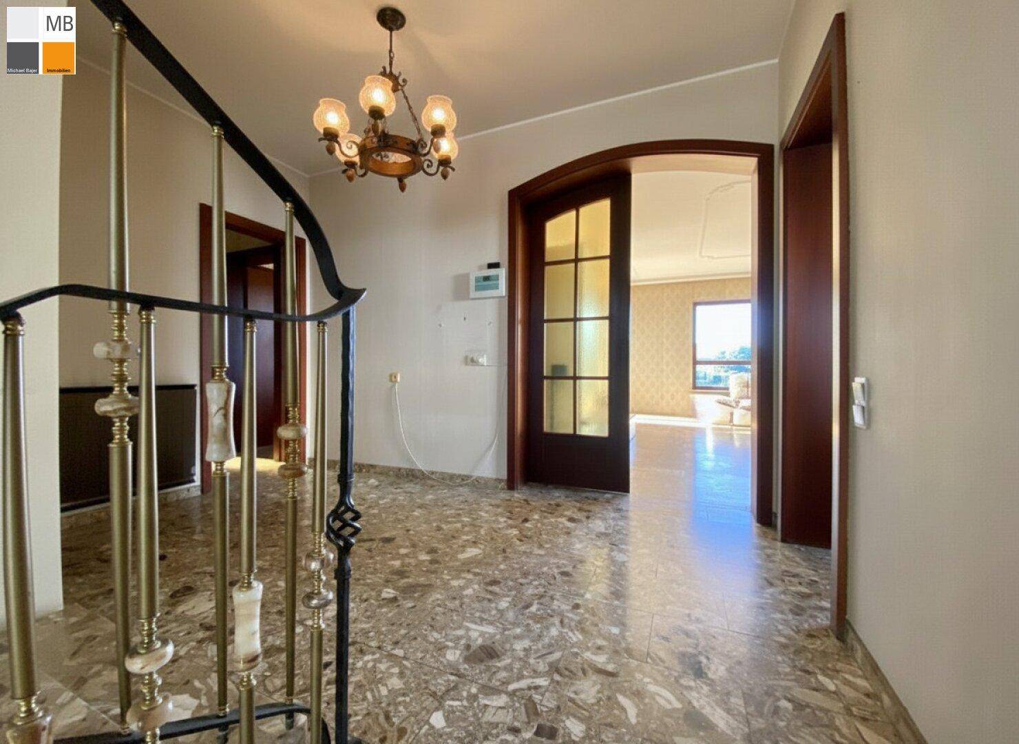 Geräumiger Eingangsbereich mit Marmorboden, eleganter Treppe und Zugang zu weiteren Räumen.