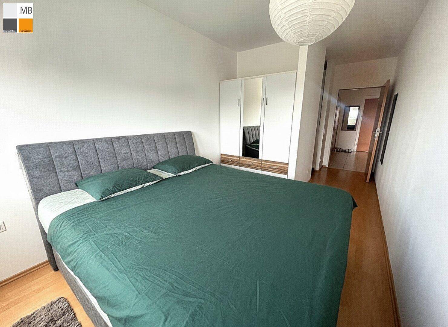 Schlafzimmer mit großem Bett, Holzfußboden und weißem Kleiderschrank.