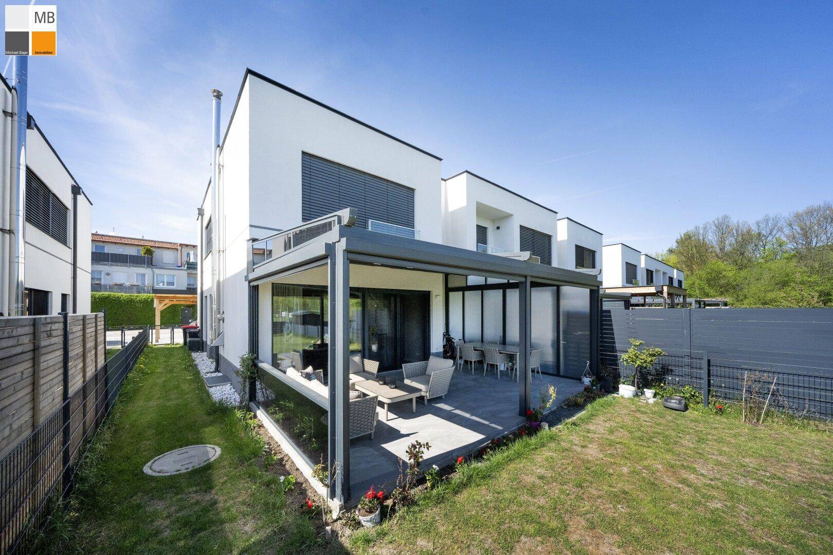 Ansicht des modernen Hauses von der Seite mit großzügiger Terrasse und weitläufigem Gartenbereich.