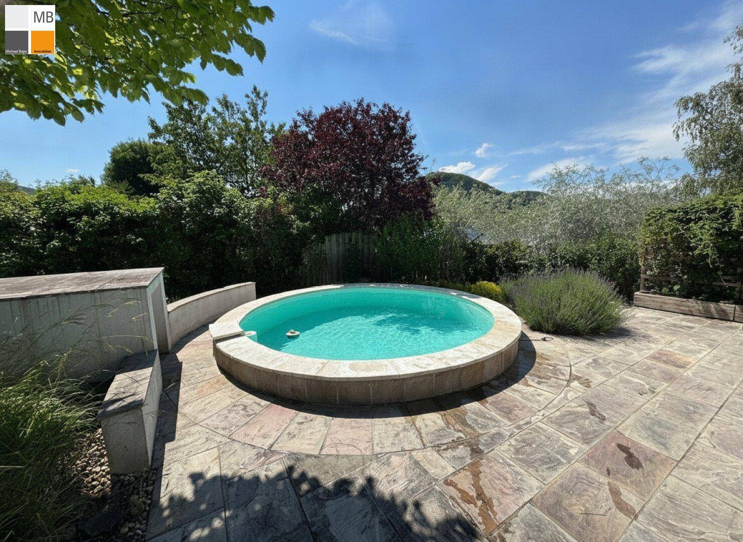 Idyllische Terrasse mit rundem Pool, umgeben von Lavendel und weitem Blick auf die grüne Landschaft.