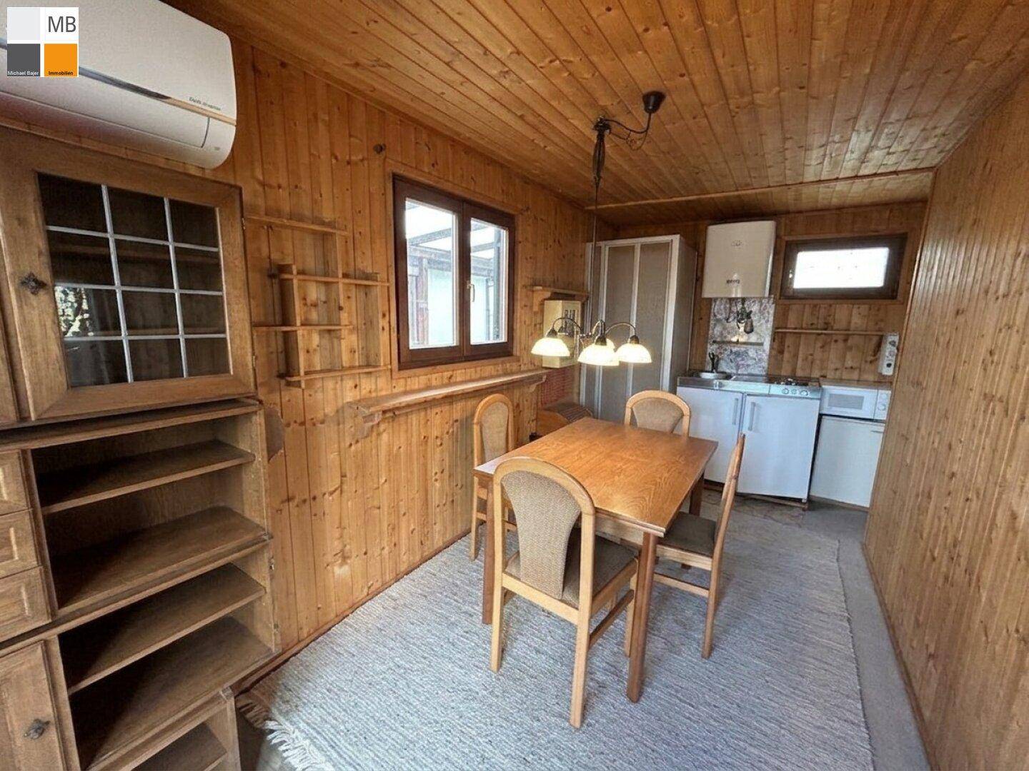 Essbereich mit Holztisch und Stühlen, angrenzend an eine kleine Küchenzeile.