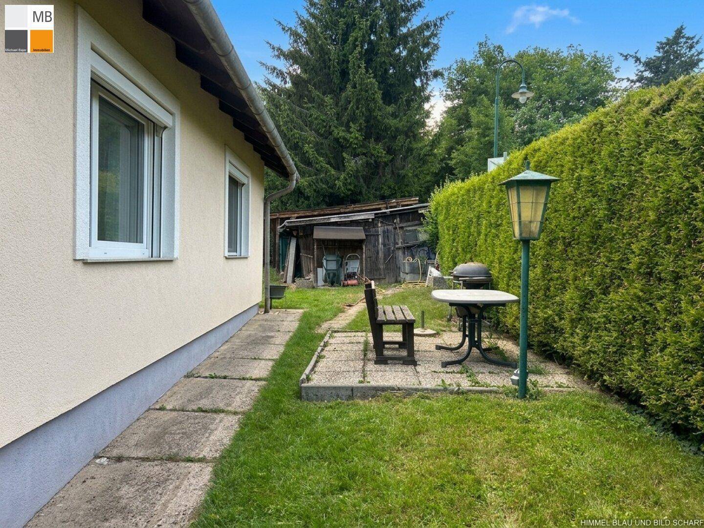 Kleiner Gartenbereich mit Grillplatz, Sitzgelegenheit und hoher Hecke als Sichtschutz.