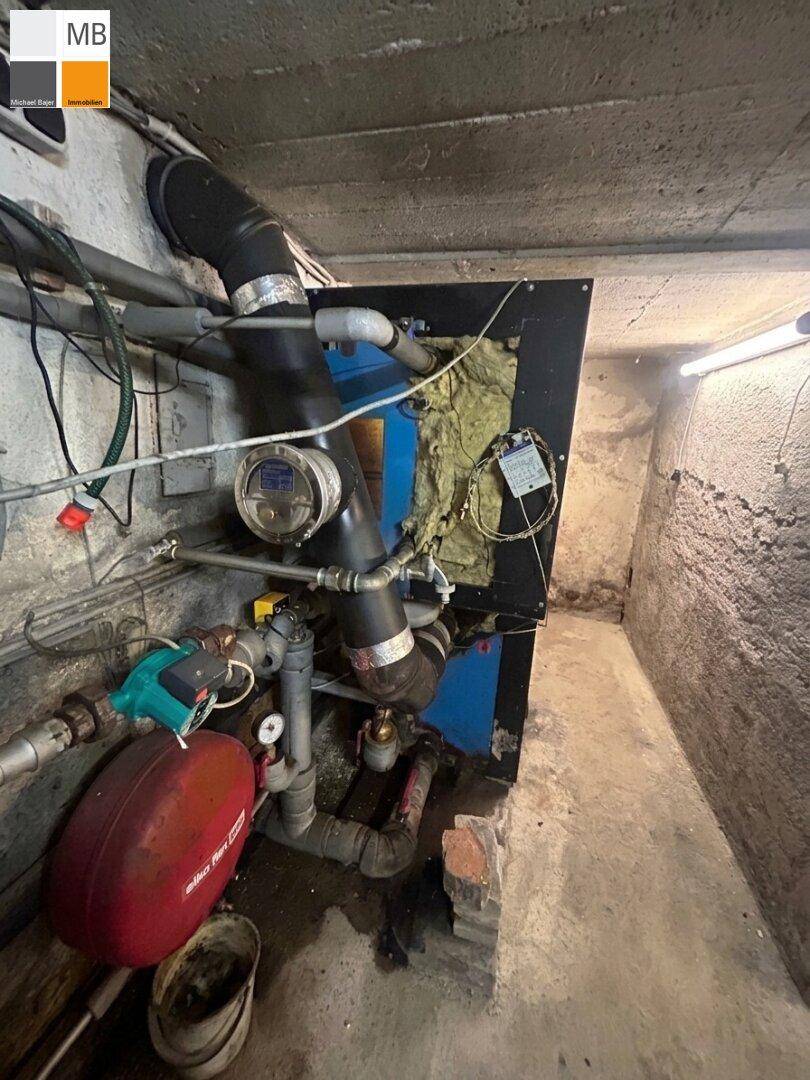 Heizungsraum im Keller mit alter Heizungsanlage und sichtbaren Rohren.