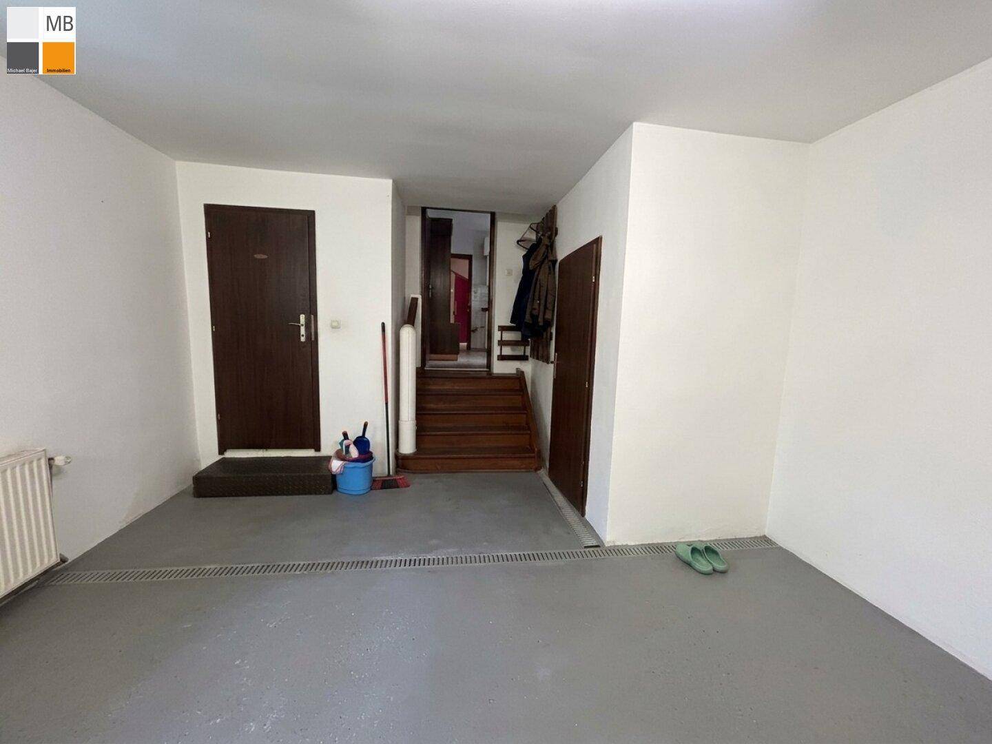 Geräumiger Flur mit Betonboden, Zugang zu weiteren Räumen und Treppe ins Obergeschoss.