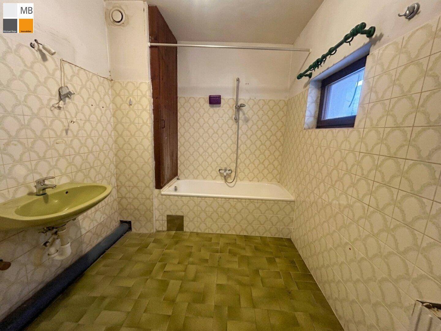 Badezimmer im 80er-Jahre-Stil mit gelben Fliesen, Badewanne und Waschbecken.
