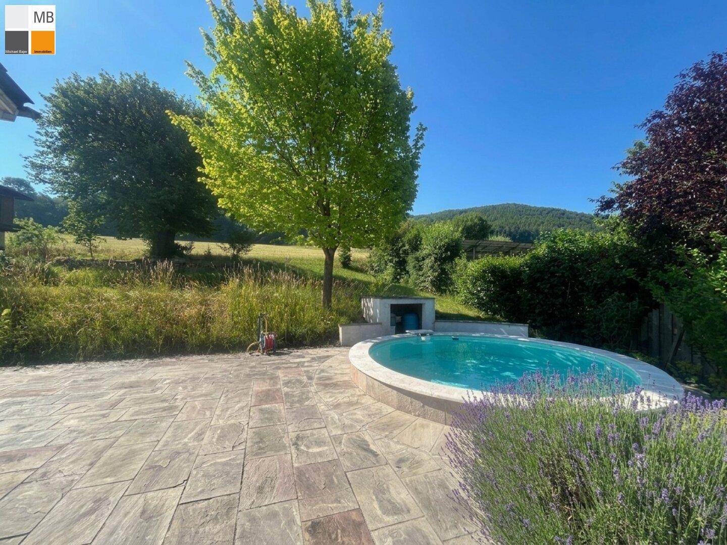 Idyllische Terrasse mit rundem Pool, umgeben von Lavendel und weitem Blick auf die grüne Landschaft.