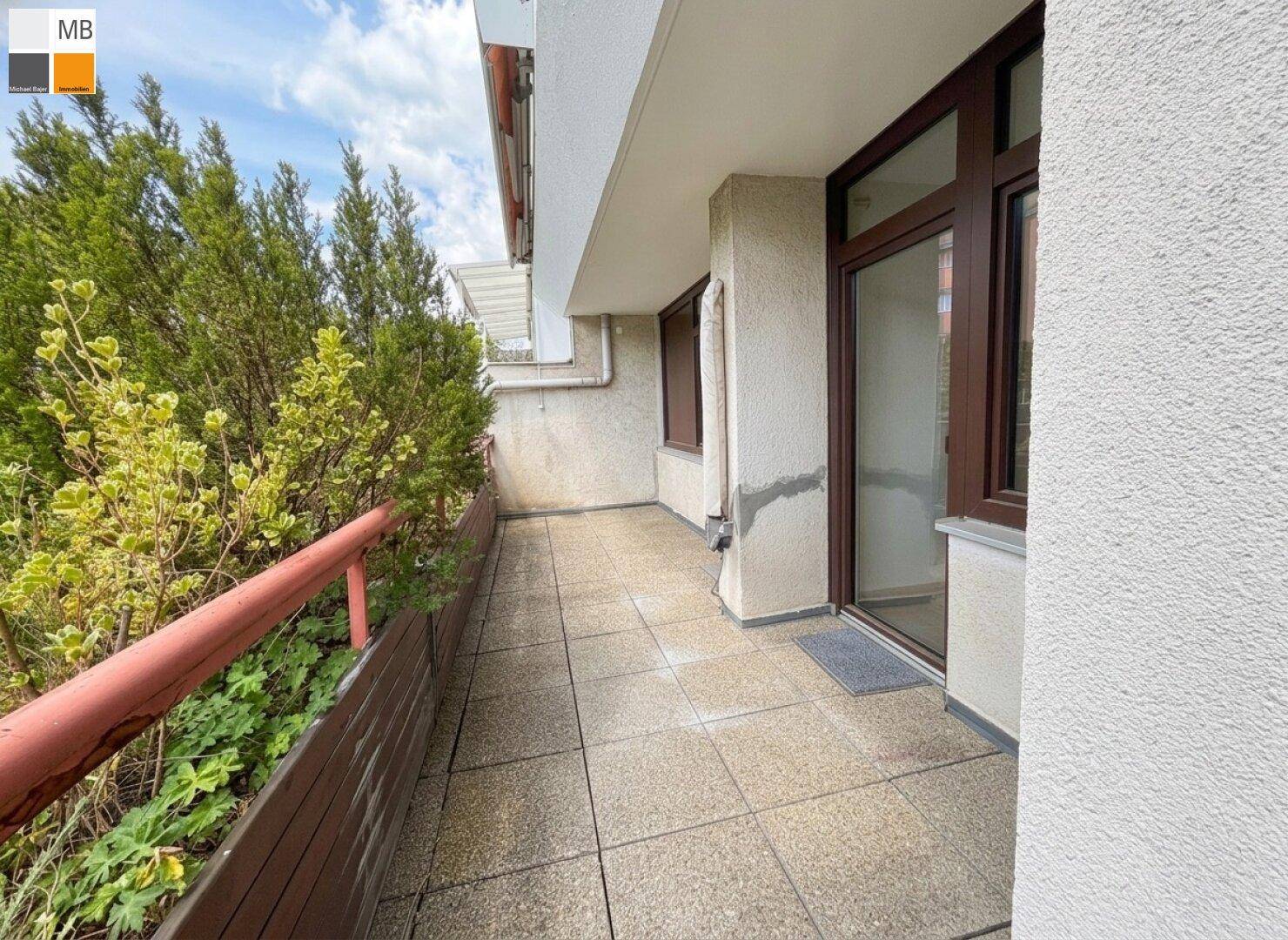 Schmaler Balkon mit Fliesenboden und grünen Pflanzen, ideal für entspannte Stunden im Freien.