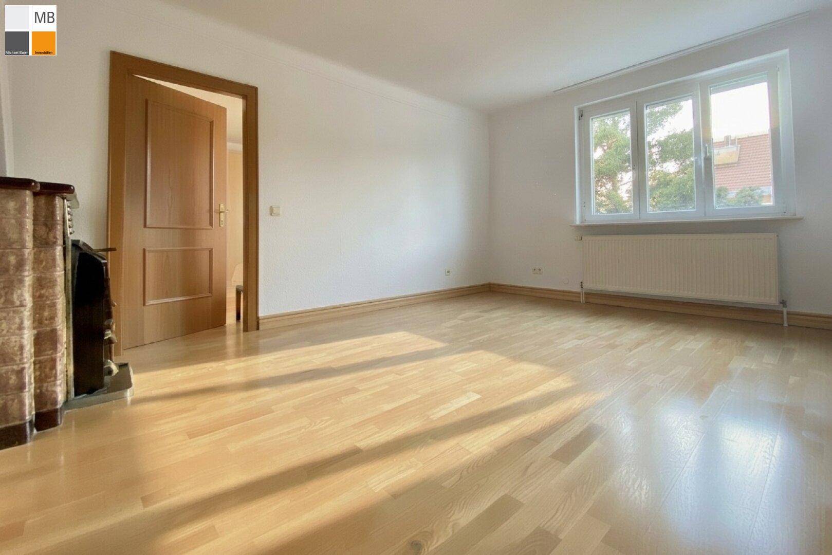 Helles Wohnzimmer mit Parkettboden und großem Fenster, bereit für individuelle Gestaltung.
