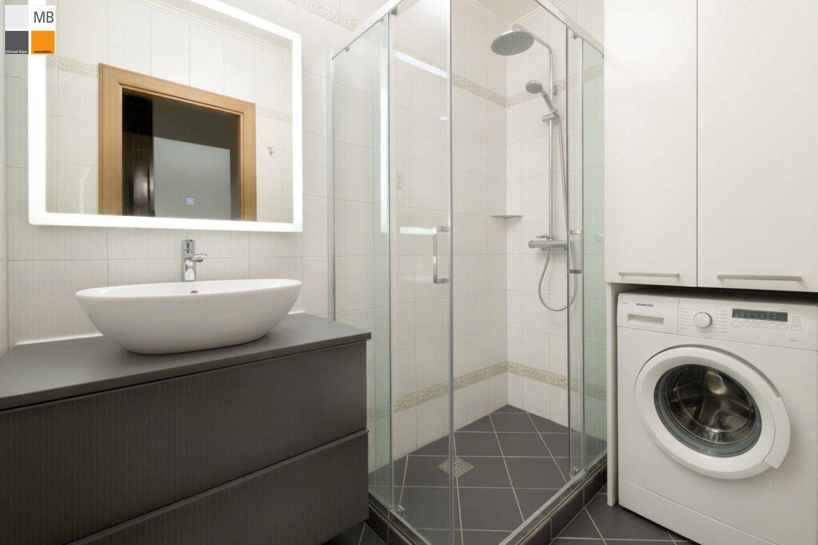 Modernisiertes Badezimmer mit Duschkabine, Aufsatzwaschbecken und Waschmaschine, hell gefliest.