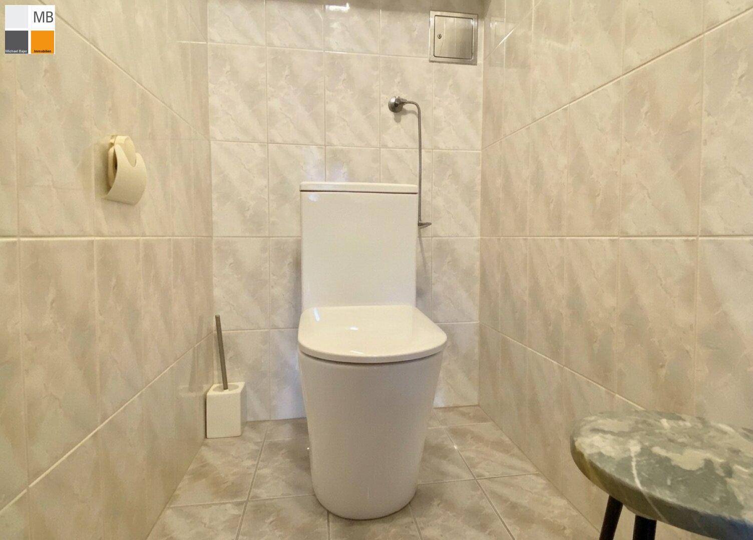Separates WC mit hellem Fliesenboden und Wandfliesen, funktional und sauber.