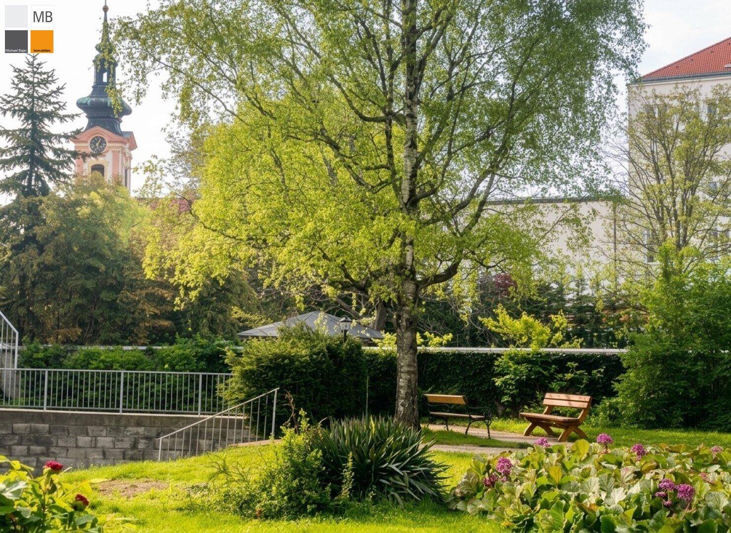 Gepflegter Gemeinschaftsgarten mit Sitzbänken und blühenden Pflanzen, ideal zum Entspannen.