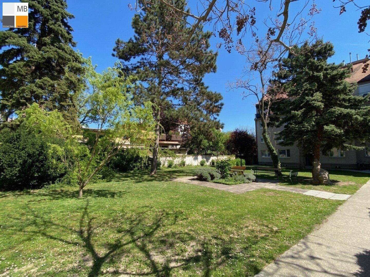 Weitläufiger Gemeinschaftsgarten mit Rasenflächen und Bäumen, bietet viel Grünfläche.